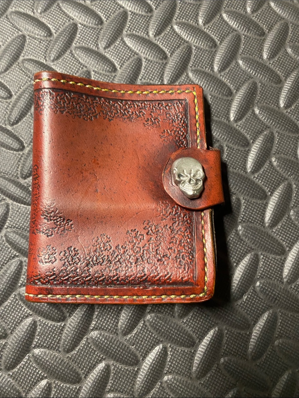 hand-carved leather wallet featuring a skull within a clock face design.